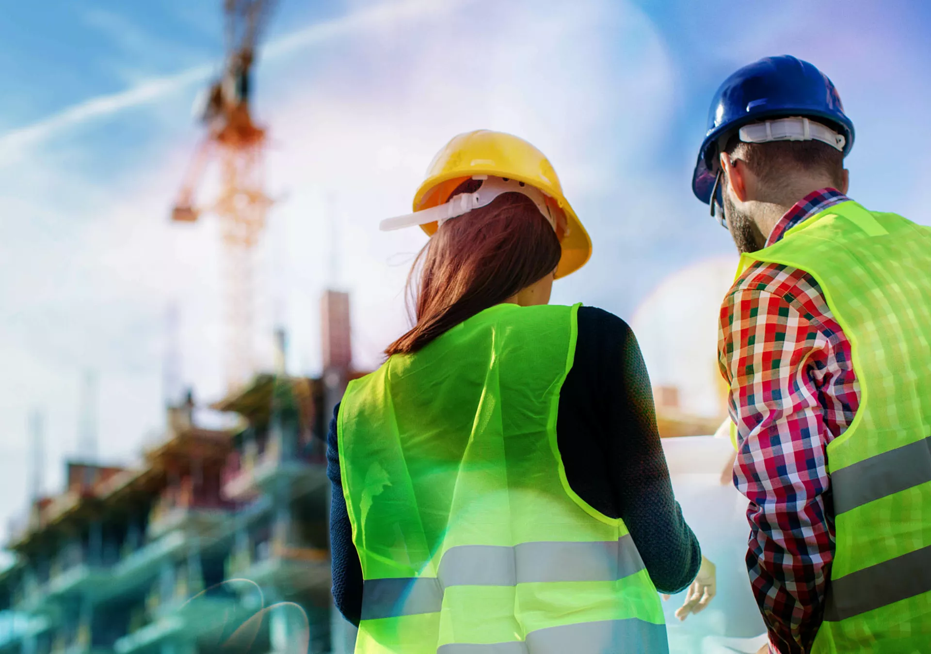 Two construction workers wearing protective gear discussing next steps