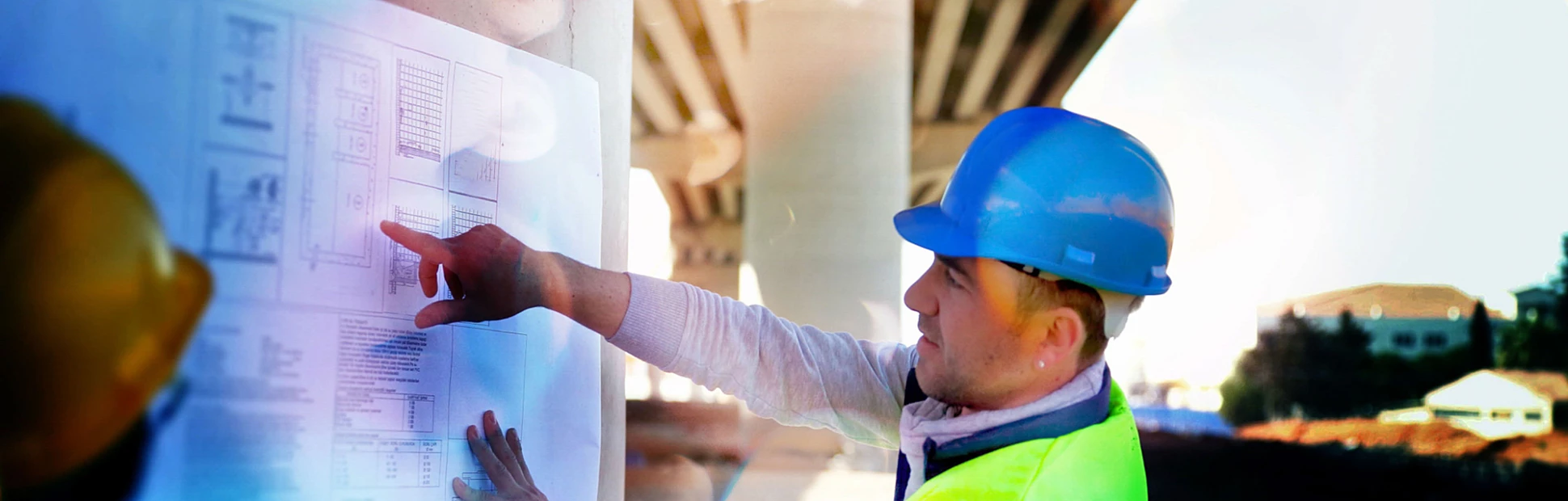 Engineers looking at construction plans and drawings under a bridge
