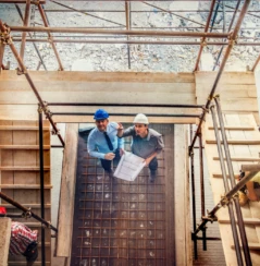 Two architects looking blueprint on a construction site