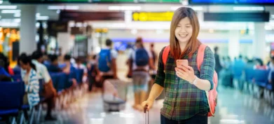 Asian traveler with luggage holding the smart mobile phone for check-in at the airport