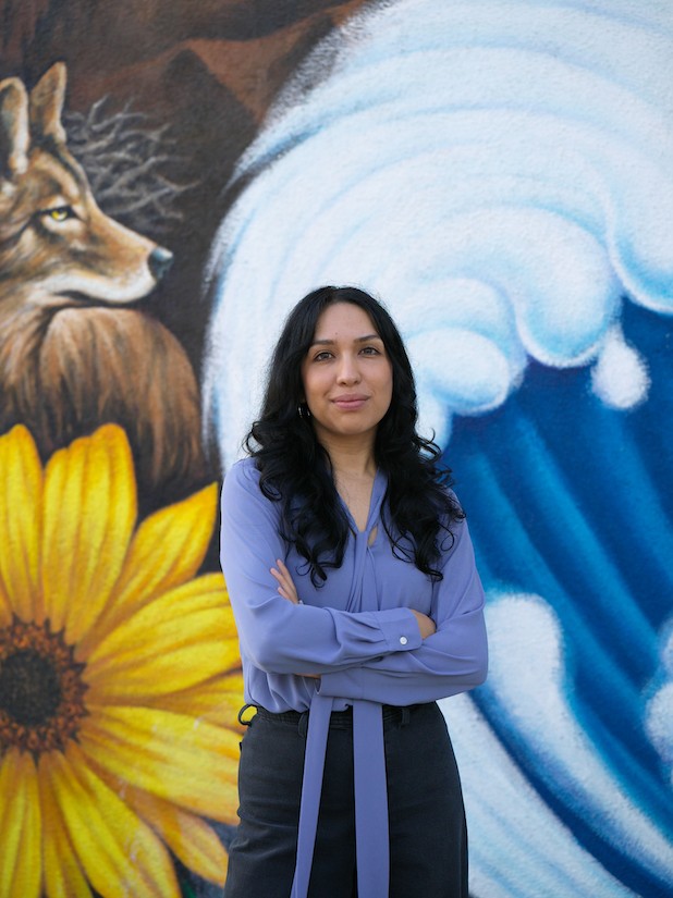 A picture of Angela Gonzales-Torres standing in front of a mural.