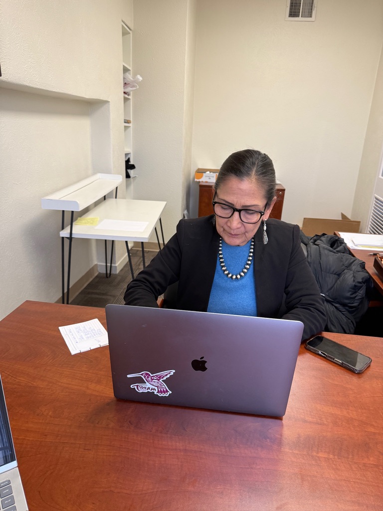 Image of Deb Haaland in front of a laptop