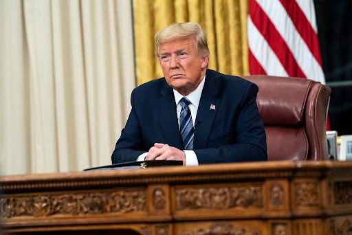 Donald Trump seated at the Resolute Desk in the Oval Office