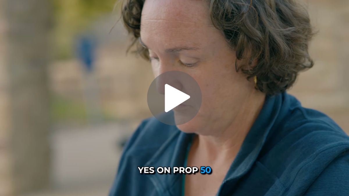 An image of a video with a play button in the center. It shows Katie Porter with a caption on the bottom reading 'Yes on Prop 50'.