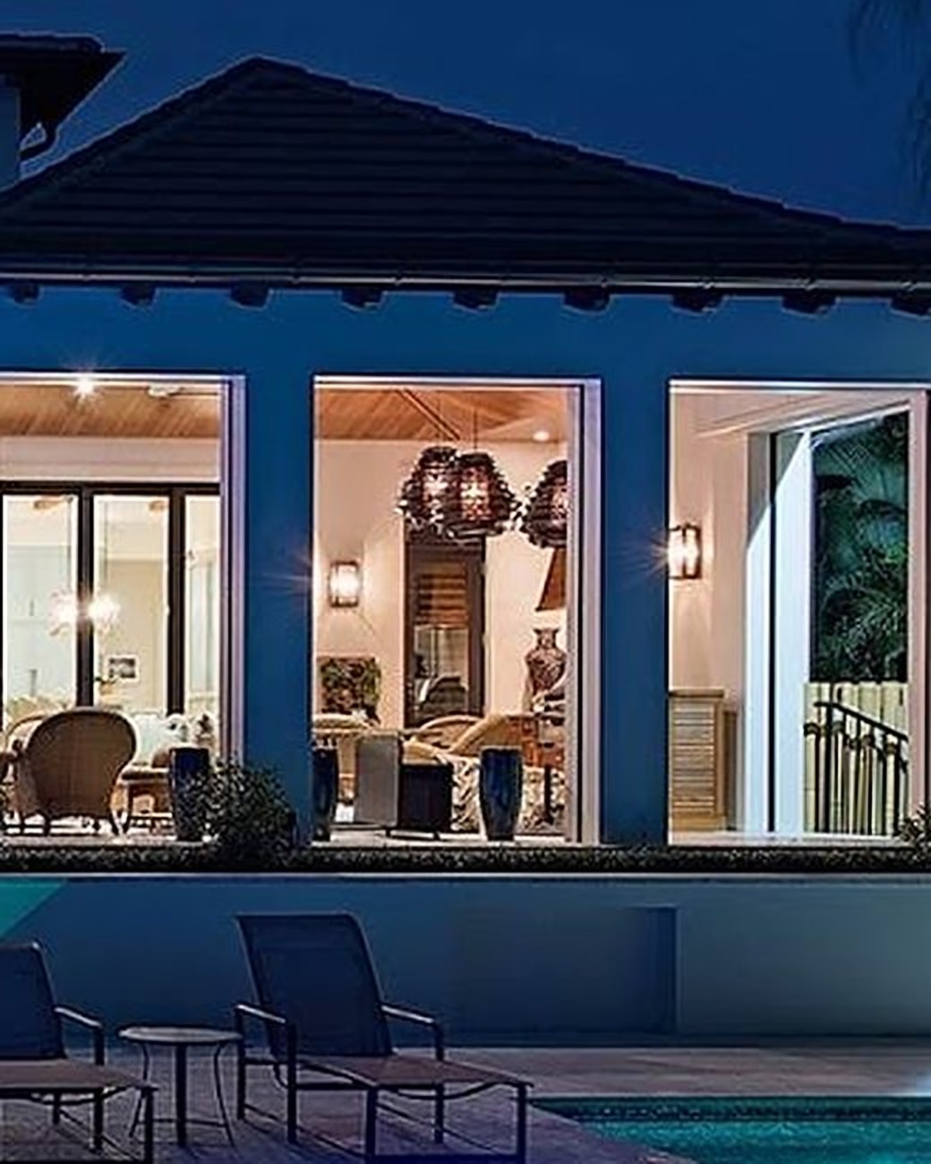 Pool reflecting the lit terrace of an estate under palms at night