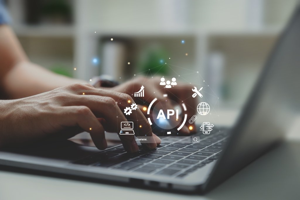 A person on a laptop with a graphic of an API concept.