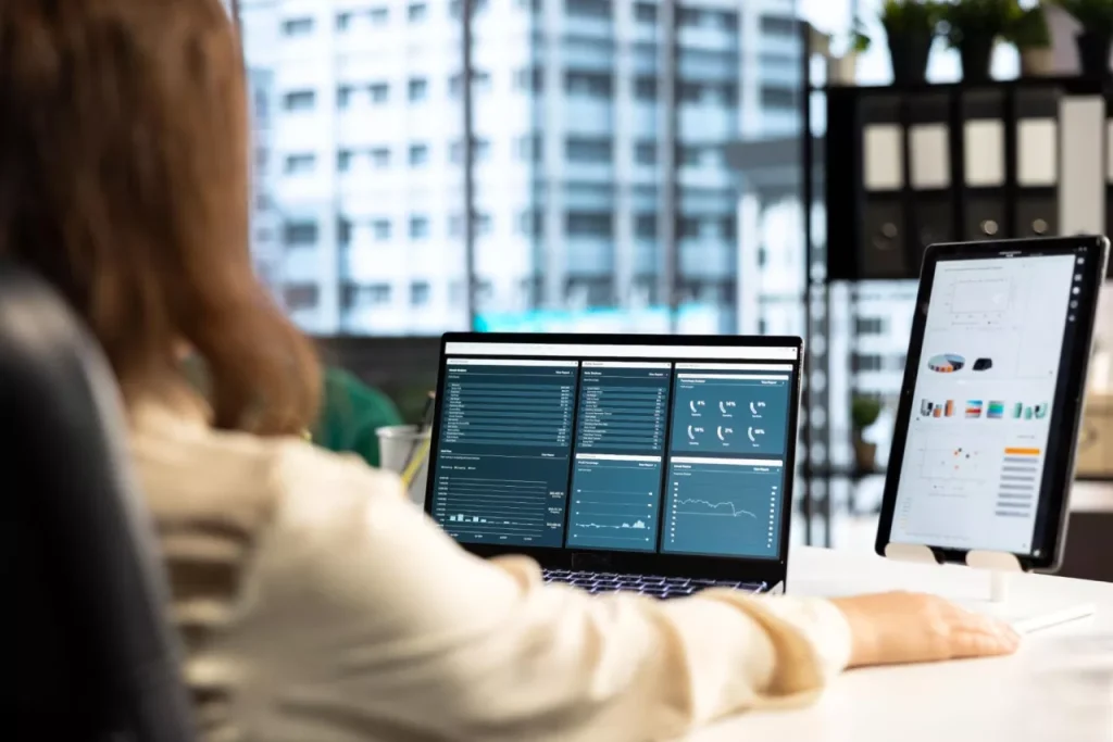 Business analyst reviewing ERP dashboards on multiple screens