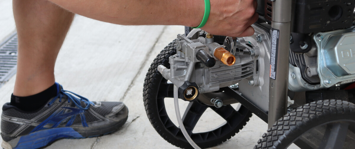 A person beginning to remove a pressure washer pump