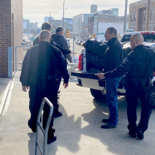 Officers helping unload gifts brought to hand out to inmates for Christmas Behind Bars through the volunteers at The ROP Shop and Outdoor Concepts.