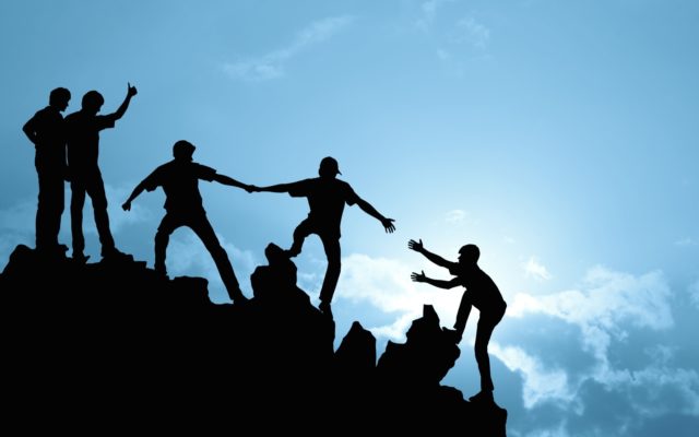 People helping each other climb a mountain