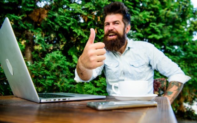 Man on computer and phone giving the viewer the thumbs up.