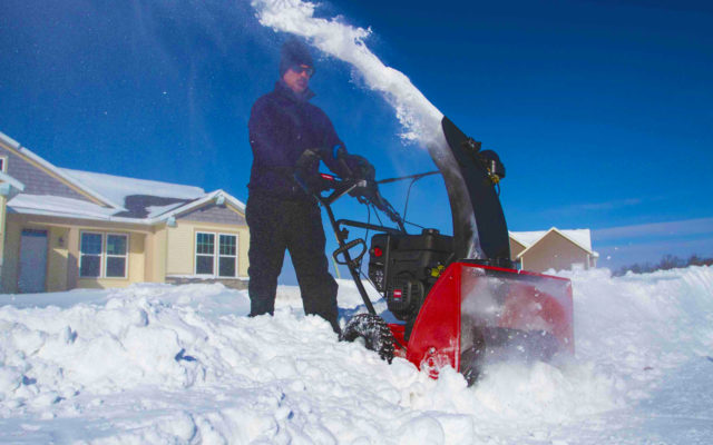 A man clearing a path through snow with his snowthrower.