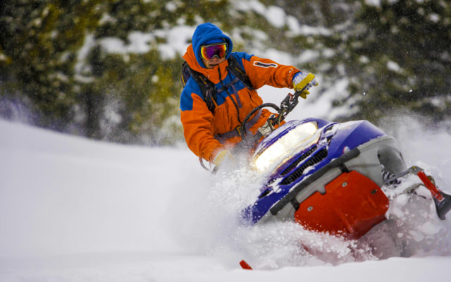 A man riding a snowmobile through the snow.