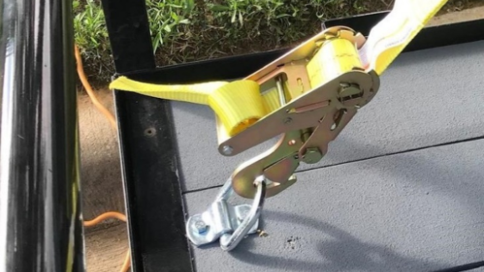 A trailer strap connected to a 'D' ring that is bolted to a trailer.