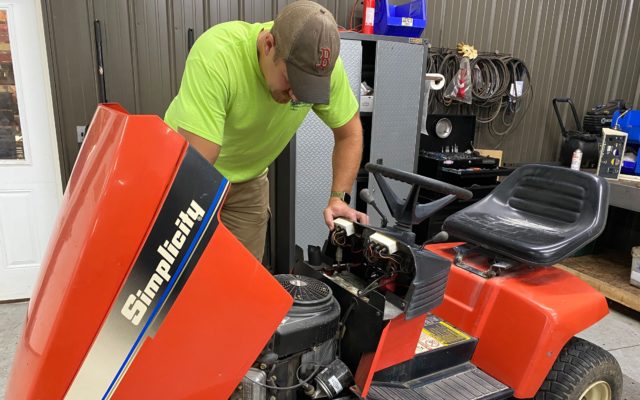 A man working on a riding lawnmower.