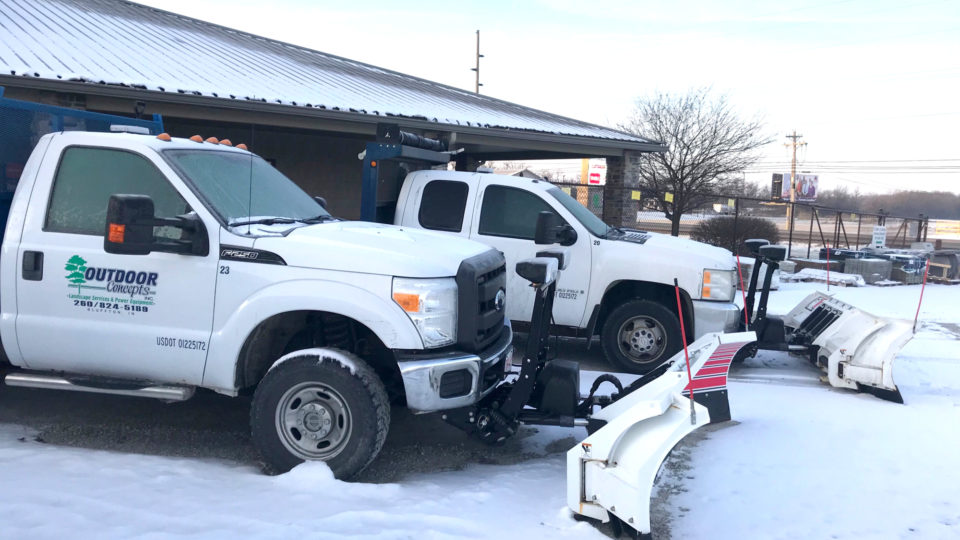 Two Outdoor Concepts trucks with snowplow attachments.