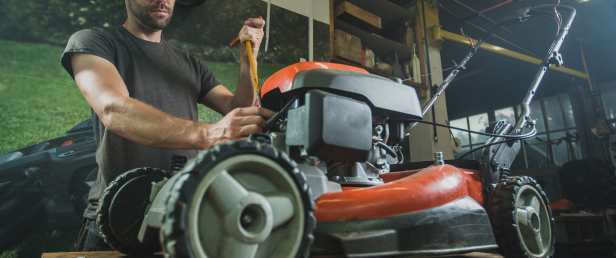 A man repairing a push mower.
