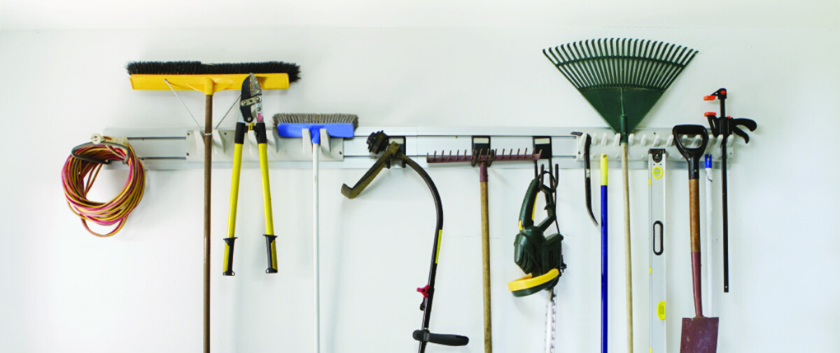 A wall in a garage with tools hanging up.