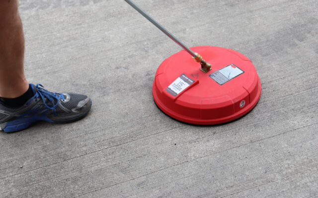 A person using a pressure washer surface cleaner