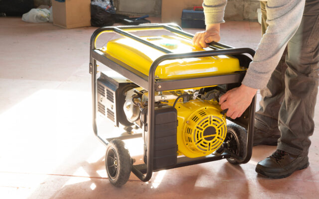 A man bending over a generator, getting ready to start it