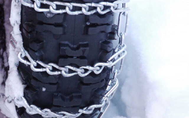 A close-up on tire chains installed on a tire with a snowy background
