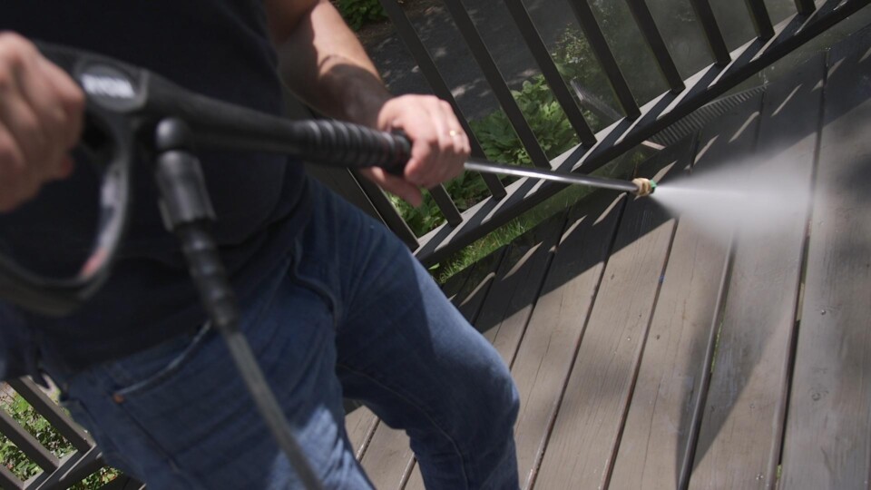 A person using a pressure washer on a porch