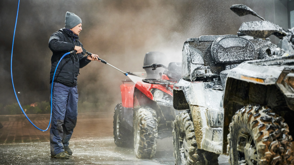 A person power washing a pair of ATVs