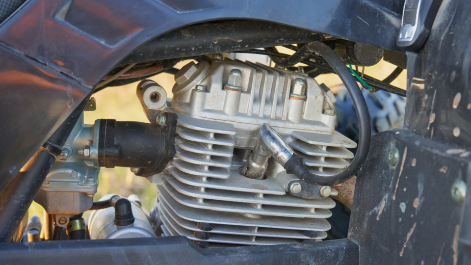 A close-up of a spark plug in an ATV engine