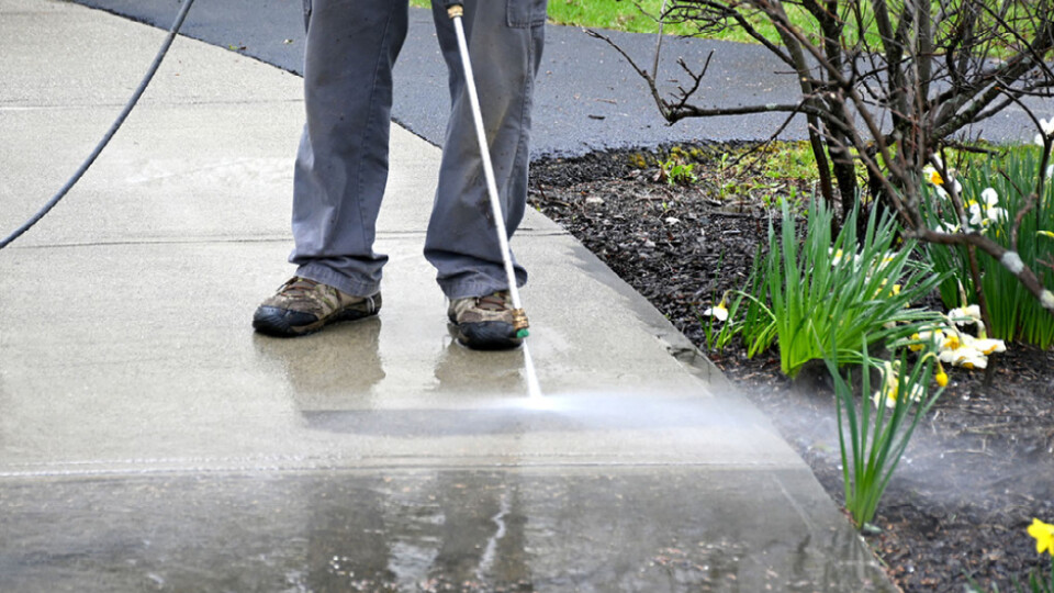 A person using a pressure washer on a driveway