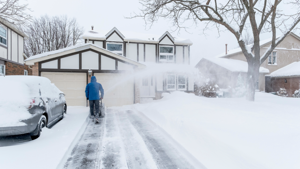 A person using a snowblower to clear snow from their driveway