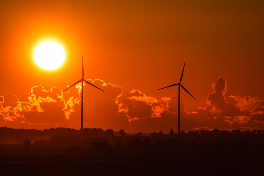 two power-generating windmills with sunset and clouds