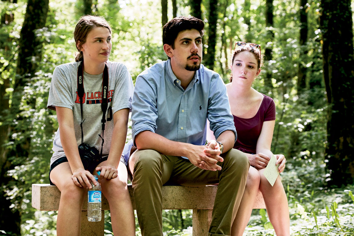 Students sitting on a bench Three students sitting on a bench