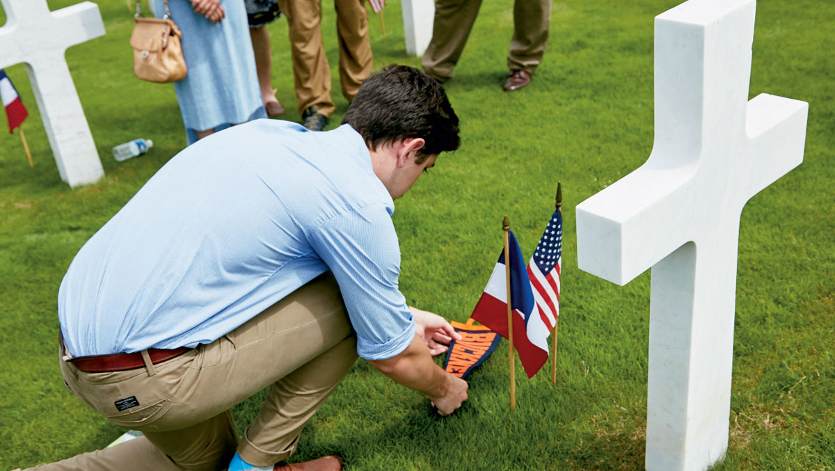 Student placing flags at a headstone Student placing flags at a military headstone