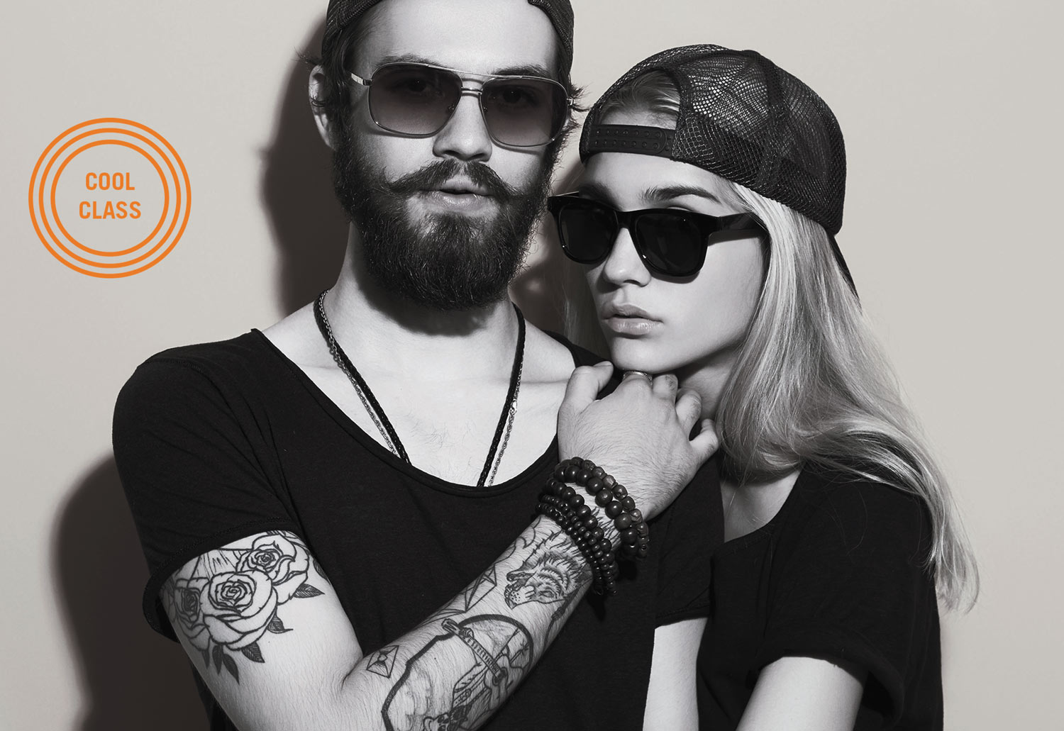 black and white image of a tattooed young man and woman standing together wearing sunglasses