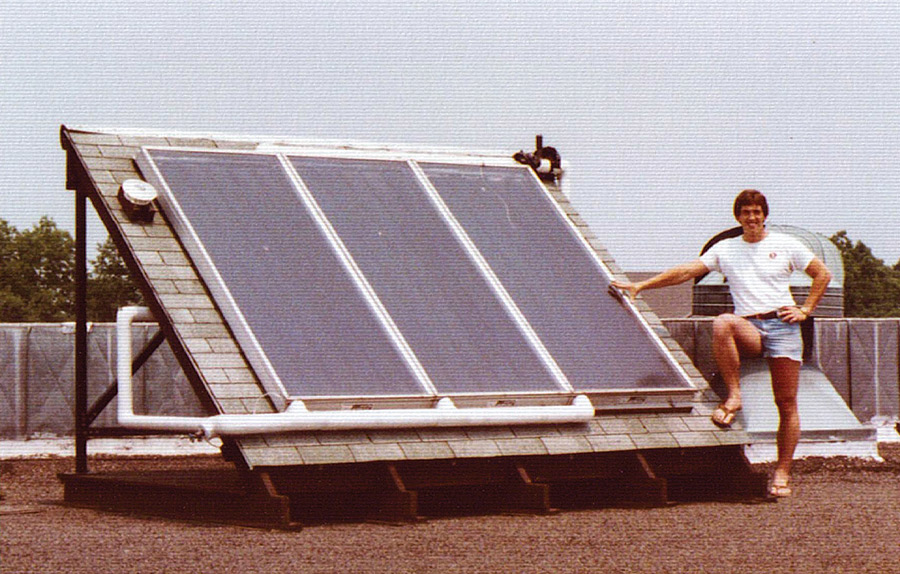 Gary Fritz on the roof with a large solar panel.