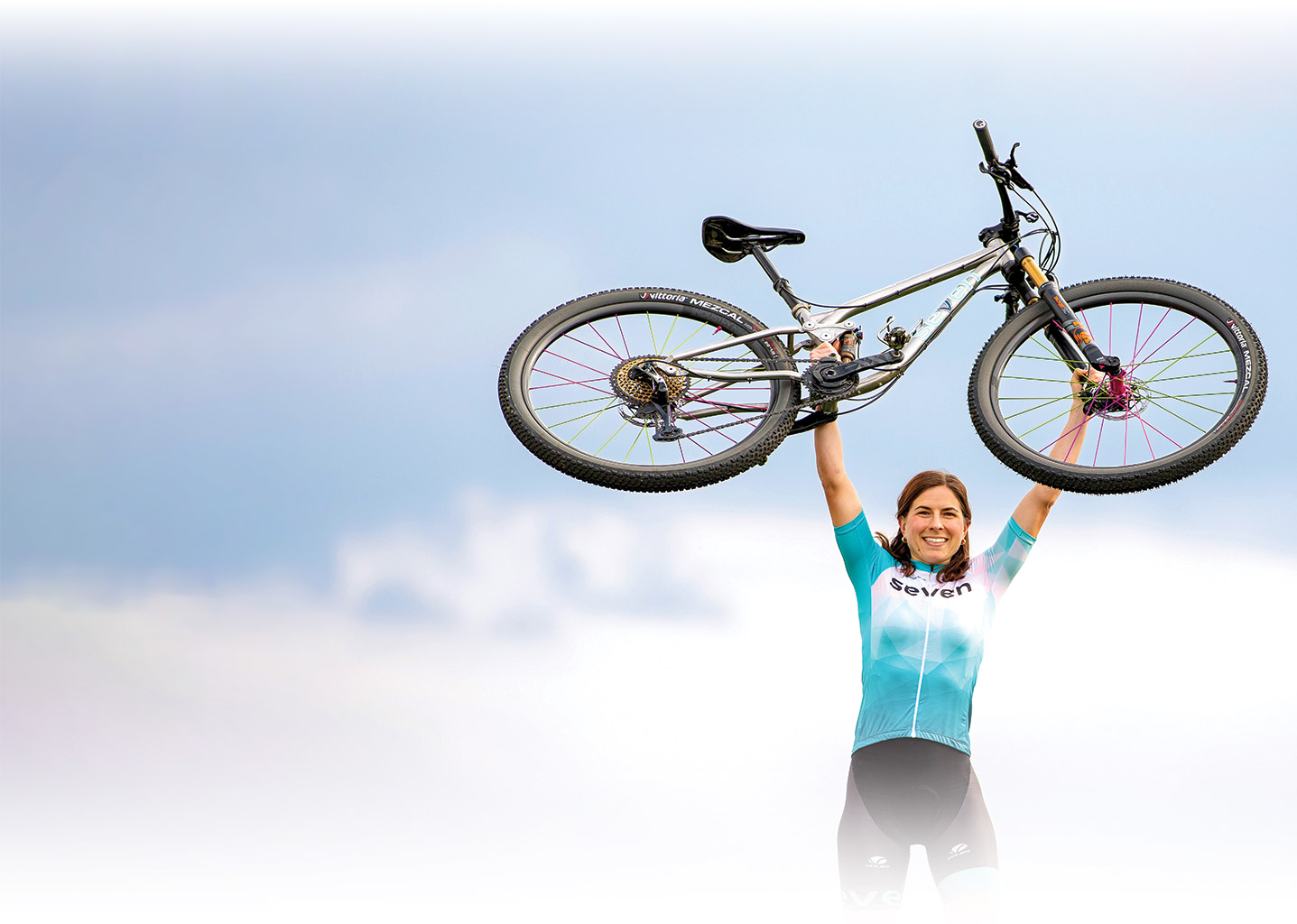 Kelly Catale holding up her bike triumphantly