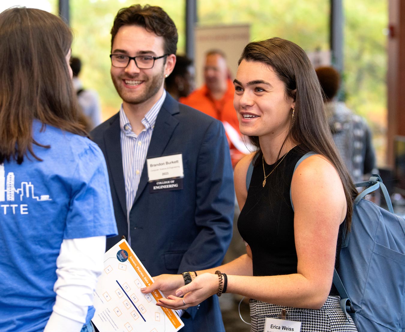 two students smile while asking questions to an associate in the Center for Career Advancement