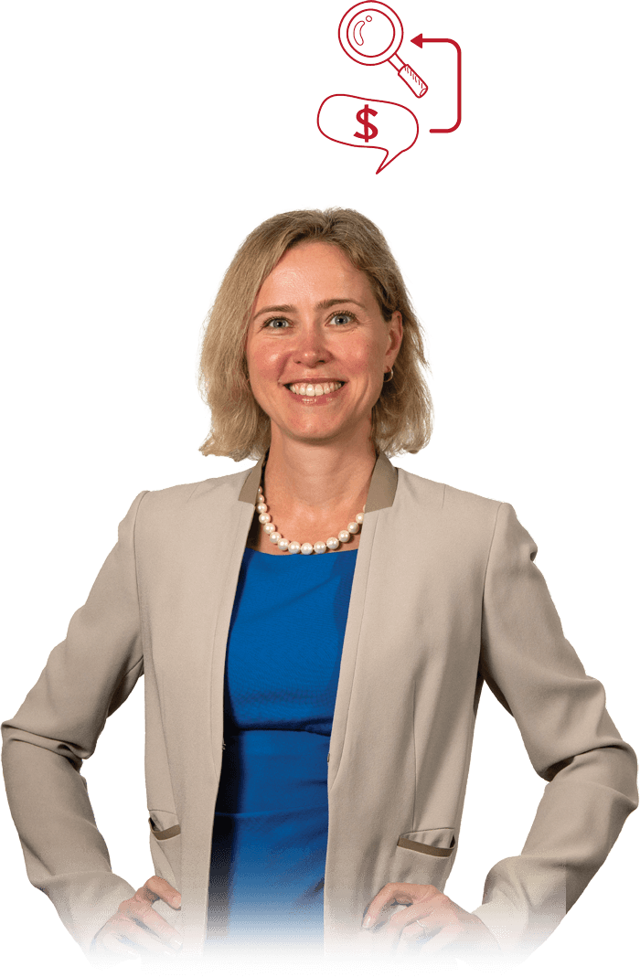 Kate Suslava in a tan jacket and blue dress with hands on her hips and smiling