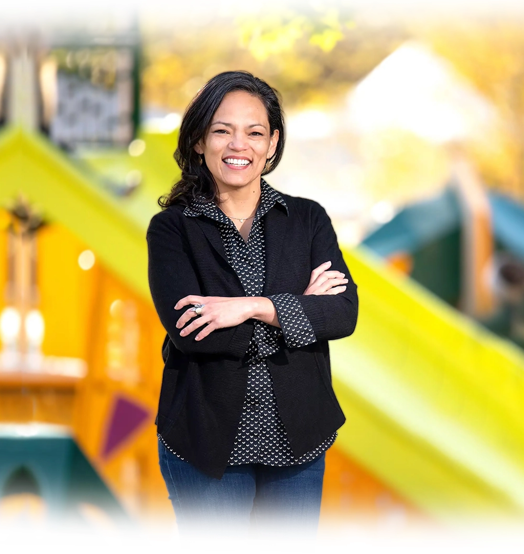 Gabriela Diego smiling with her arms crossed in front of a playground