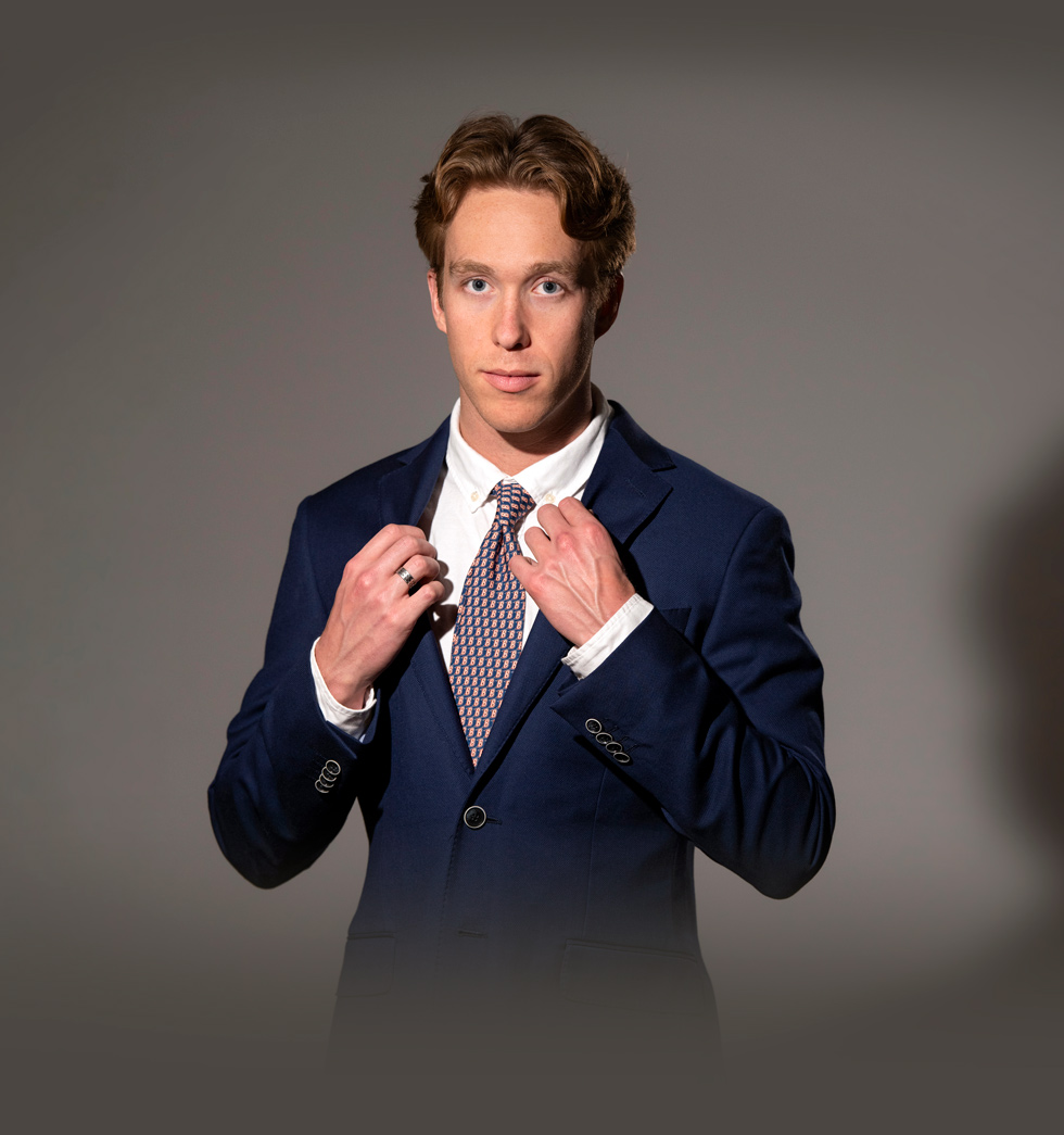 Alec Baker grabbing the Lapels of his suit