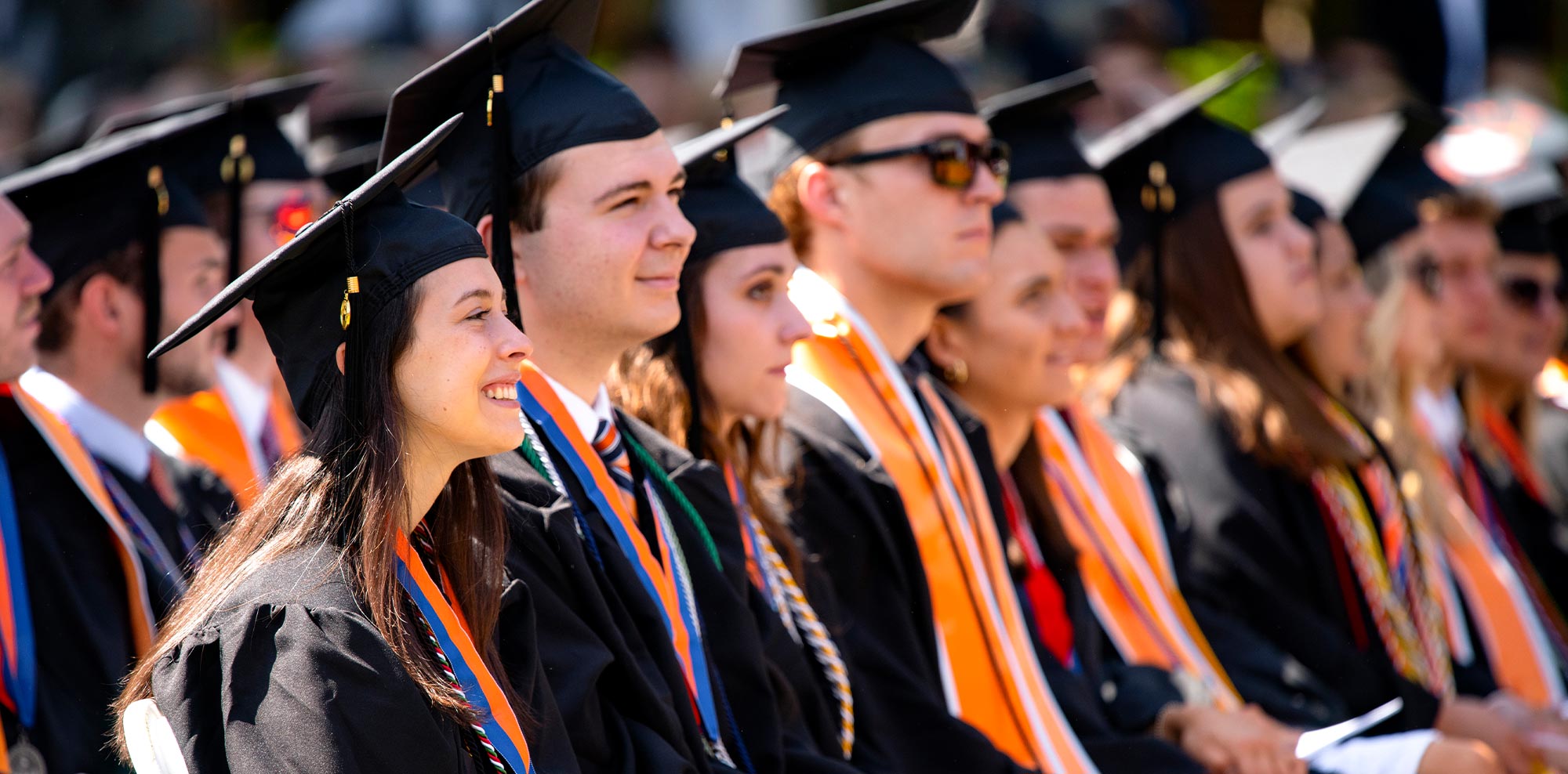 view down a row of smiling Bucknell grads seated at a graduation ceremony