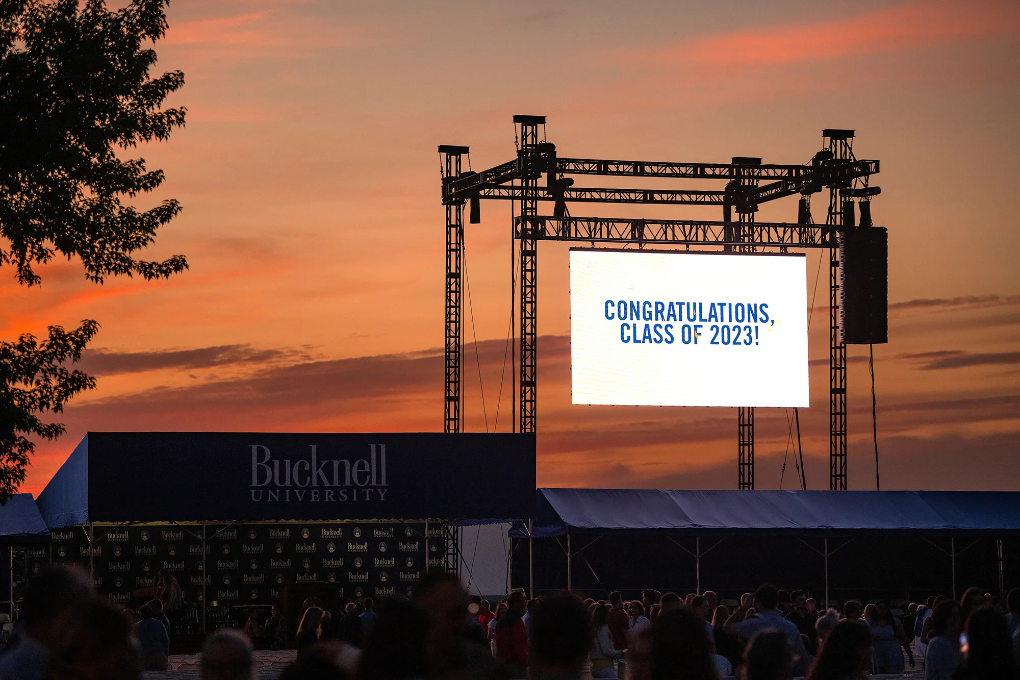 The pre-Commencement candlelighting ceremony with the sunset in the background and a large hanging screen displaying CONGRATULATIONS, CLASS OF 2023!