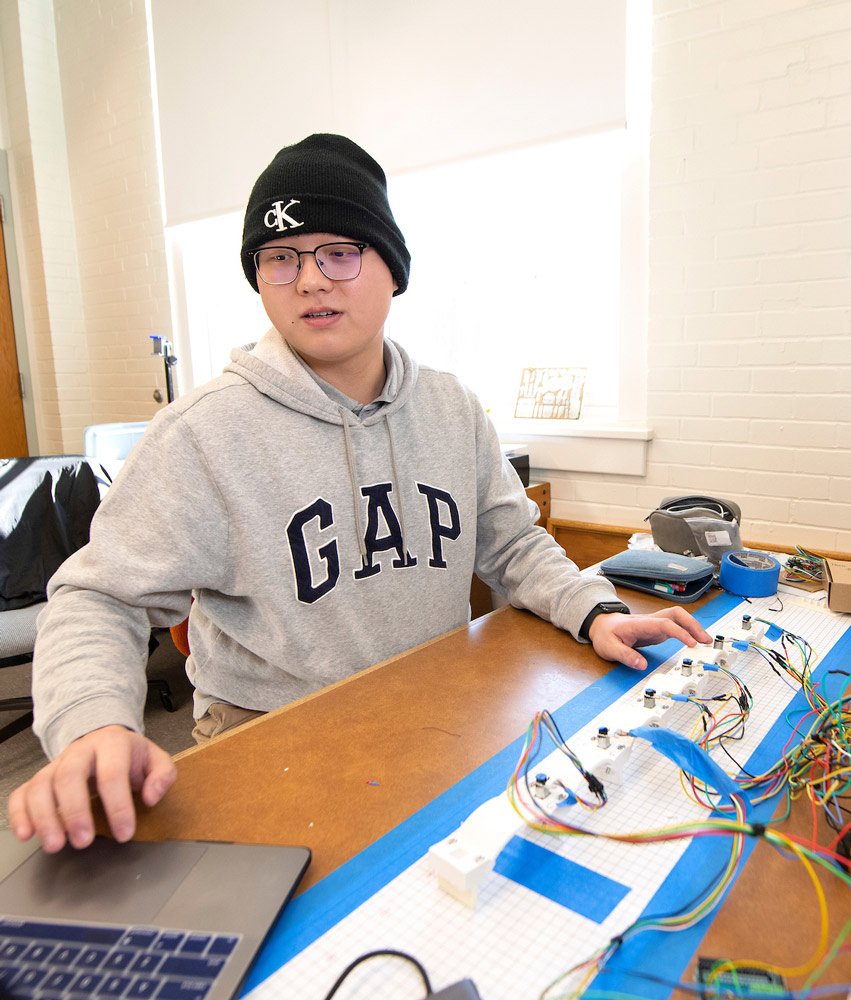 Student on laptop working with robotic equipment
