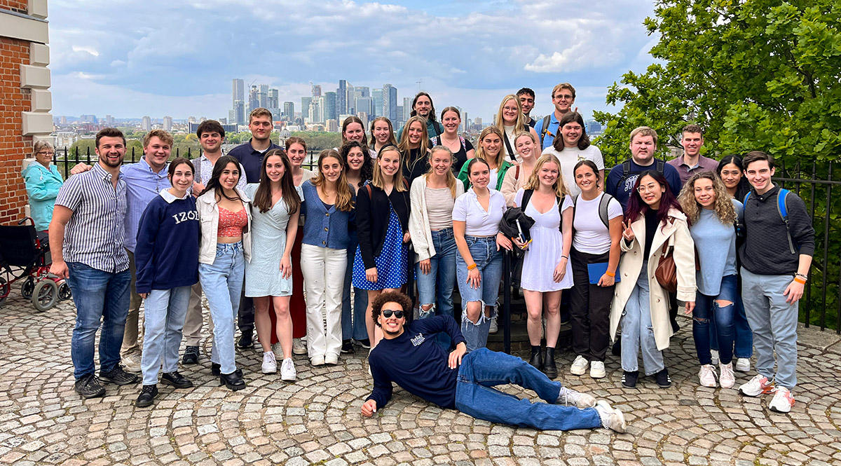 large group of students smiling for a photo with skyline behind them