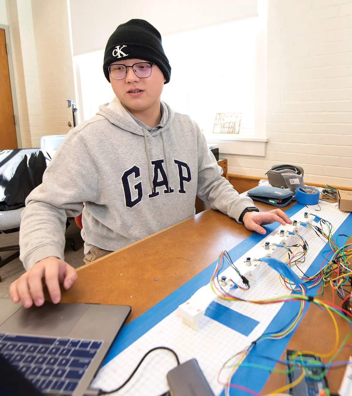 mechanical engineering major Harry Shi working on wiring units with his laptop