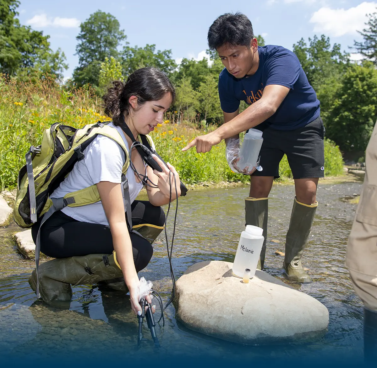 Students collecting water samples in a small stream