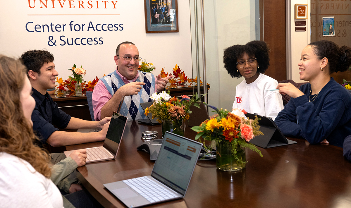 staff and students sitting together and smiling in the Center for Access & Success