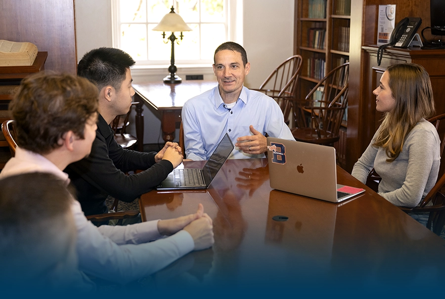 Assistant Registrar Vince Pellegrini sitting with a team of students