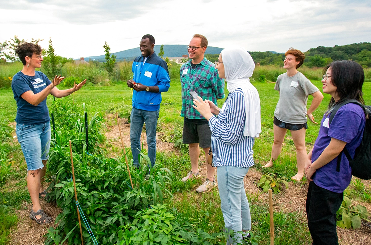 Small group of Bucknell students standing in a garden area outside on a gloomy day at Bucknell Farm, a 5-acre regenerative farm that produces organic produce, increases biodiversity and supports interdisciplinary learning; Every year, hundreds of students visit and volunteer here at Bucknell Farm.