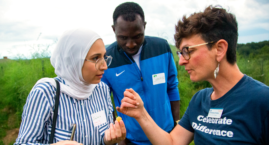 two women and a man speaking outside in field